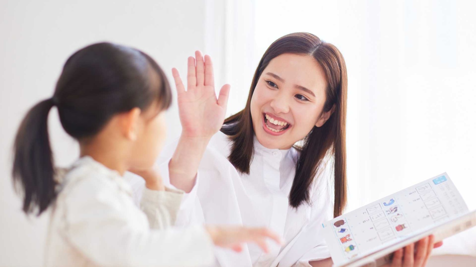 Teacher smiling and high-fiving a young student