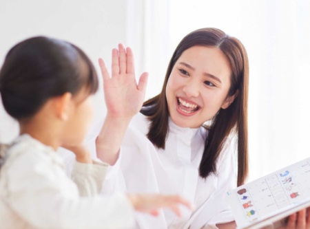 Teacher smiling and high-fiving a young student