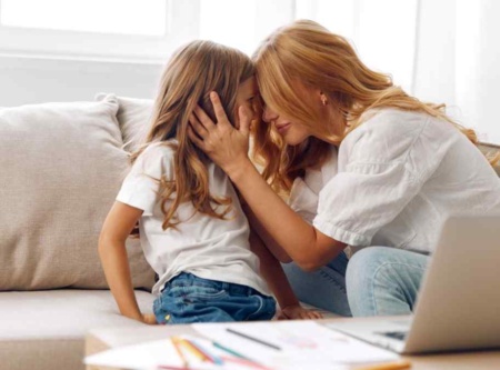 Parent holding her daughter's face, foreheads touching.